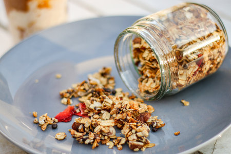 Homemade granola in a glass jar on a white wooden tableの写真素材