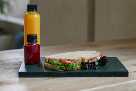 Sandwich with tomato juice and lettuce on wooden table in cafe.の写真素材