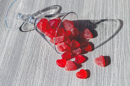 Red heart-shaped candies in a glass on a wooden background.
Valentine's Day