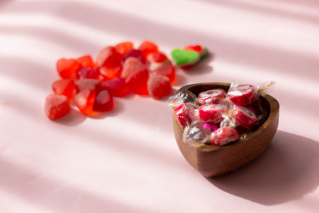 Candy in a wooden bowl on a pink background with shadows.の写真素材