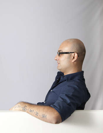 man sat at an open window, side elevation wearing glasses, drapes in the backgroundの写真素材