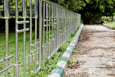 landscape horizontal chrome patterned fence and unswept bordered path lush greenery at Botanical Gardens Bangalore India patterns shapes crop margins copy area empty spaceの写真素材