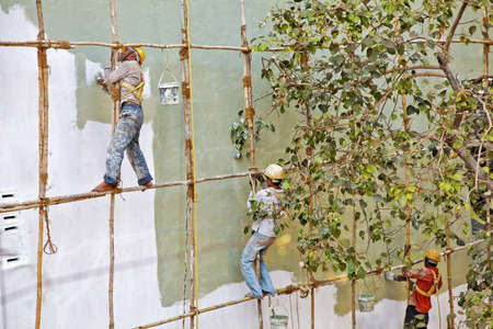 Mumbai Indian horizontal of exterior bare foot decorators wooden scaffold India painting a building wallのeditorial素材