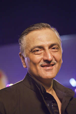 Rakesh Thakore Chivas Regal workshop, Mumbai, India December 10, 2011   Vertical portrait of Rakesh Thakore under colored lights, renowned Indian textiles designer, partner in Abraham   Thakore sat on a bar stool waiting to be interviewed for televisionのeditorial素材