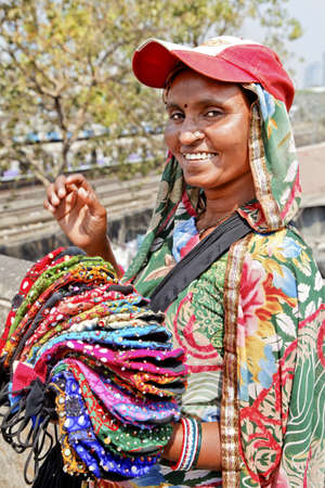 Mumbai tourist spot, Dhobhi Ghat, protrait of colorful smiling purse street vendor with baseball hatのeditorial素材