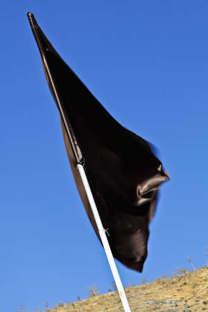 Diagonal shot, portrait, vertical of a plain silky black flag waving in a gentle breezeの写真素材
