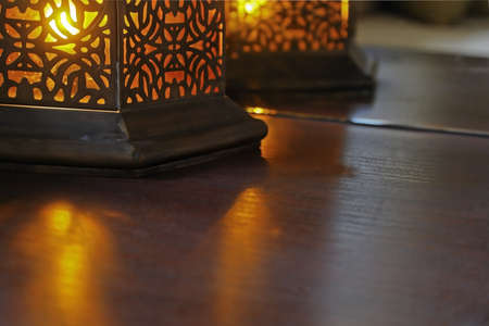 Amber colored buld in a oriental eastern design table casts beams over table surface and reflections in mirrorの写真素材