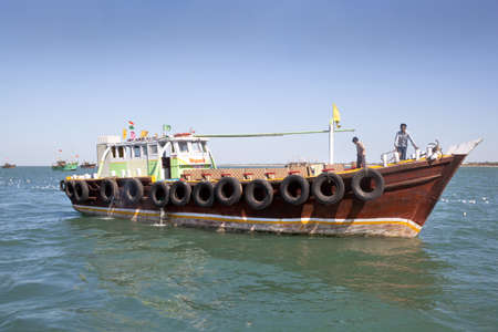 Dwarka Roadtrip  Offshore ferry boat at Dwarka with crew under a fairly clear blue sky  with other vessels in the distance and seagulls on the water surface and in flight  Gujarat India  March 27 2013のeditorial素材