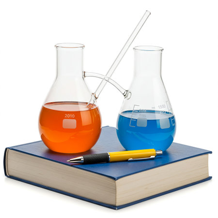 Laboratory glassware with colorful liquid and book on white background.の素材