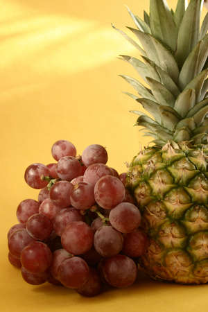 Pineapple and grapes on yellow background の写真素材