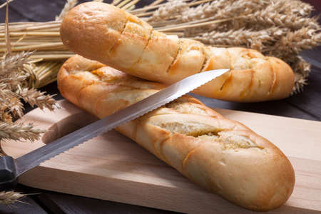 Baguettes lying on a wooden chopping board.の写真素材