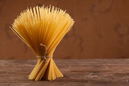 Bunch of macaroni standing upright on a wooden table.の写真素材