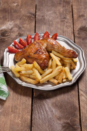 Roasted chicken leg with french fries on a metal plate.の写真素材