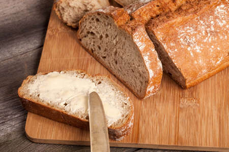 A slice of bread with butter on a chopping board.