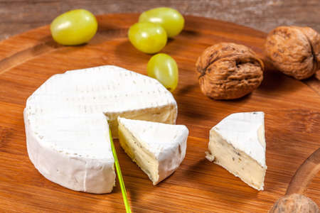 Blue cheese and grapes on a wooden board.