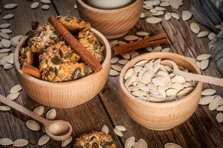 Cookies with pumpkin seeds and cinnamon with a glass of milk on a wooden background. Selective focus.の写真素材