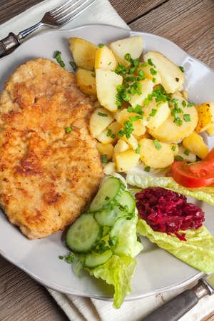 Fried pork chop with potatoes and vegetable salad.の写真素材