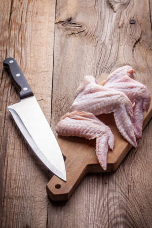 Fresh chicken wings on wooden board on tableの写真素材
