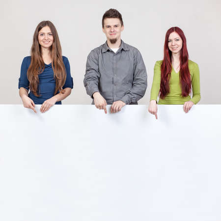 Three young friends pointing at the white boards.