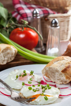 Tasty breakfast. Fried eggs with radish and bread roll.の写真素材