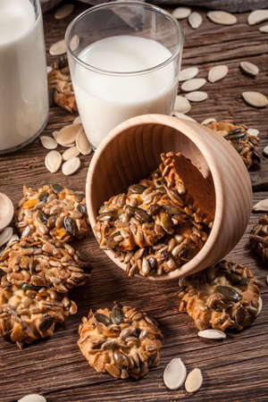 Cookies with pumpkin seeds and cinnamon with a glass of milk on a wooden background. Selective focus.の写真素材