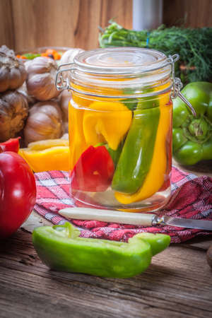 Multi-colored homemade pickled peppers on a wooden table.の写真素材