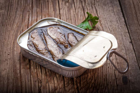 Sprats in oil in a can on a wooden table.の写真素材