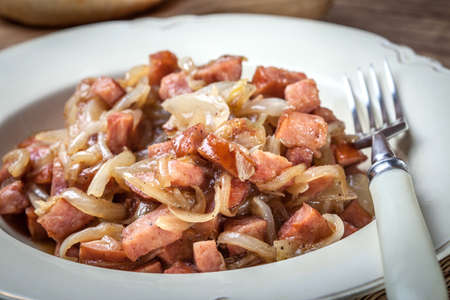 Stewed onions with sausage on a plate.の写真素材