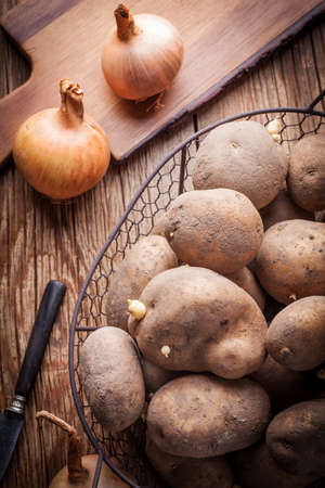 Organically grown potatoes in a metal basket on a wooden table.の写真素材