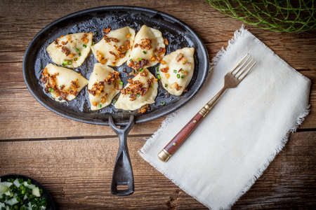 Dumplings with meat, onions and bacon on a cast iron skillet. Selective focus.の写真素材