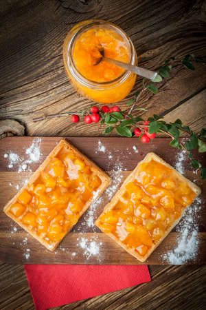 Waffles with peach jam on wodden board.の写真素材