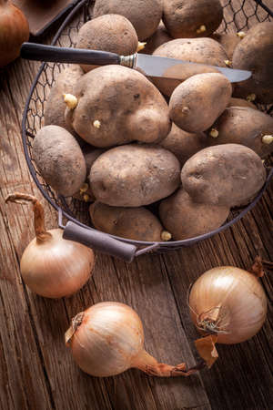 Organically grown potatoes in a metal basket on a wooden table.の写真素材