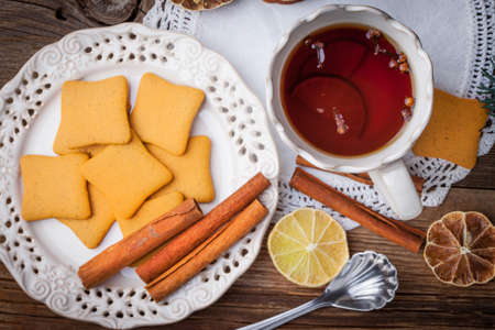 Hot tea with citrus, cinnamon, cloves and honey on a wooden table.