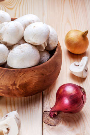 Fresh white mushrooms in a wooden bowl ready to be cleaned.の写真素材