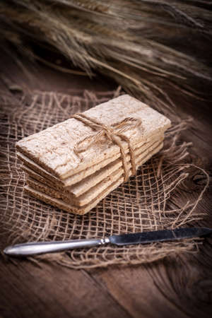 Dry diet crisp breads with ears of wheat on a wooden table. Shallow depth of field.の写真素材