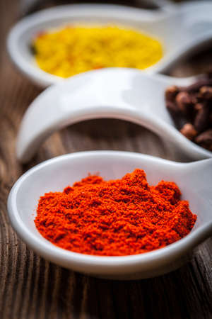 Different spices in a white spoons on the wooden background.の写真素材