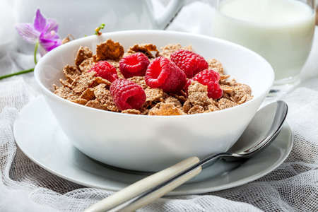 Healthy breakfast - bowl of cereals with  raspberries on a wooden table.