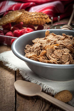 Healthy breakfast - bowl of cereals with raspberries on a wooden table.