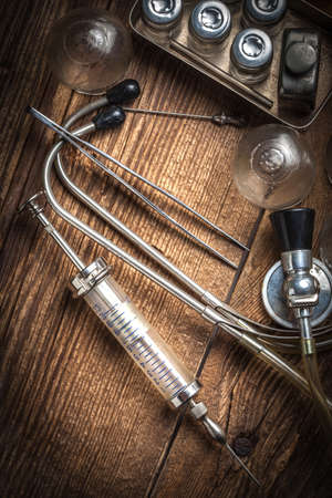 Retro syringe, stethoscope and medical cupping glass on a wooden table. Shallow depth of field.の写真素材