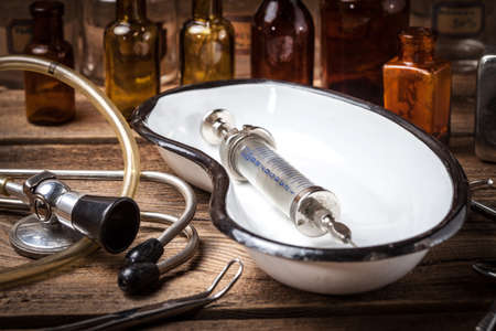 Retro syringe, stethoscope and medical cupping glass on a wooden table.の写真素材