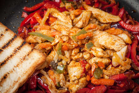 Fried chicken pieces with vegetables in a pan.の写真素材