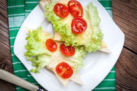 Delicious sandwich with tomatoes, cheese and lettuce on wooden table.の写真素材