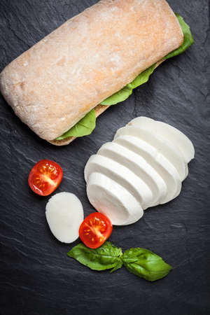 Mozzarella, tomato and basil on a dark gray stone.の写真素材