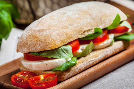 Ciabata with mozzarella, tomato and basil on a wooden table. Selective focus.の写真素材