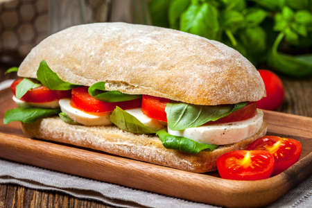 Ciabata with mozzarella, tomato and basil on a wooden table. Selective focus.の写真素材