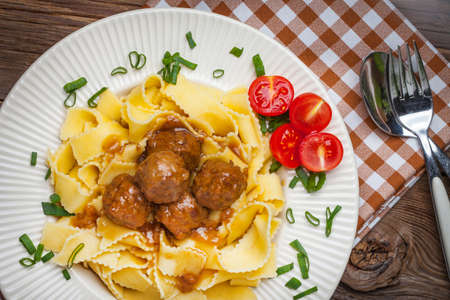 Tagliatelle, meatballs in dark sauce and tomato on a wooden background. Selective focus.の写真素材