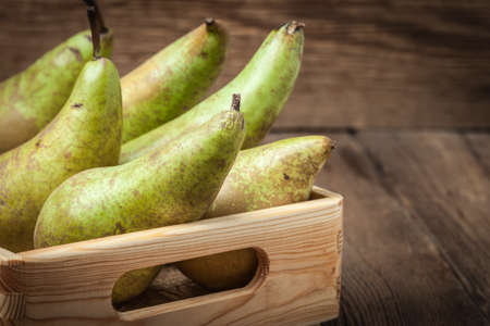 Fresh pears in a box on wooden background. Selective focus.の写真素材