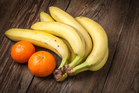 Bananas and orange on a wooden background.の写真素材