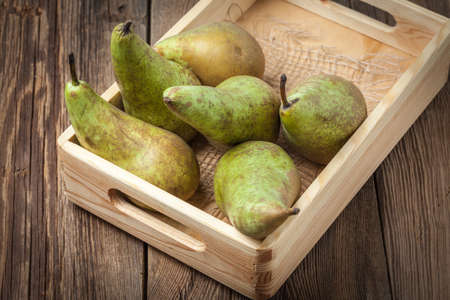 Fresh pears in a box on wooden background. Selective focus.の写真素材