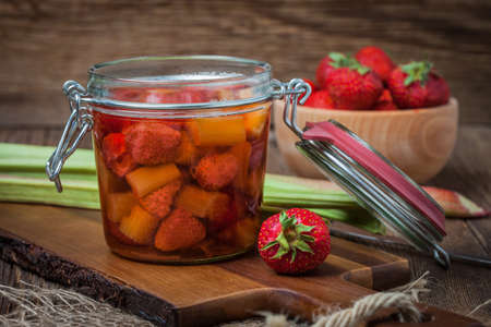 Homemade compote of rhubarb and strawberries on wooden table.の写真素材